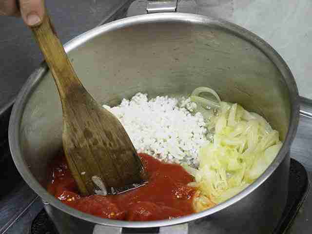 玉葱を炒め、トマトと米を入れる